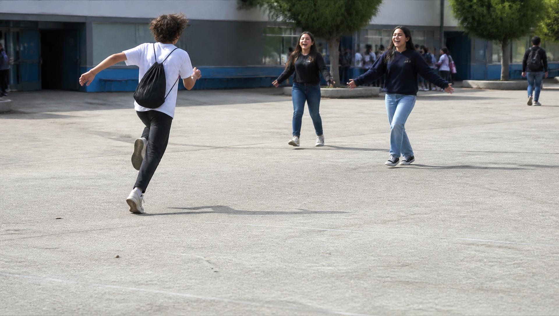 Jongere rent lachend met een rugzakje over een schoolplein