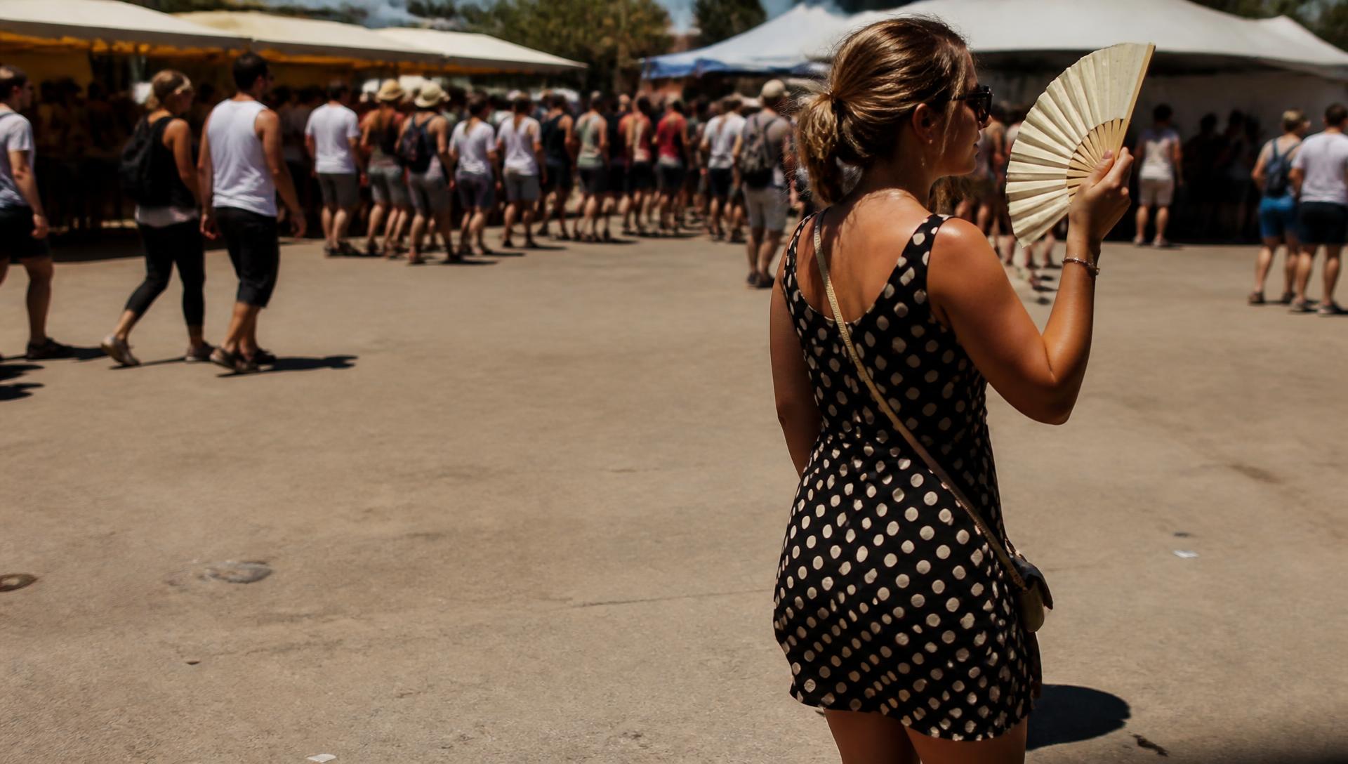 Bezoeker koelt zichzelf met een waaier op een zomers buitenevenement