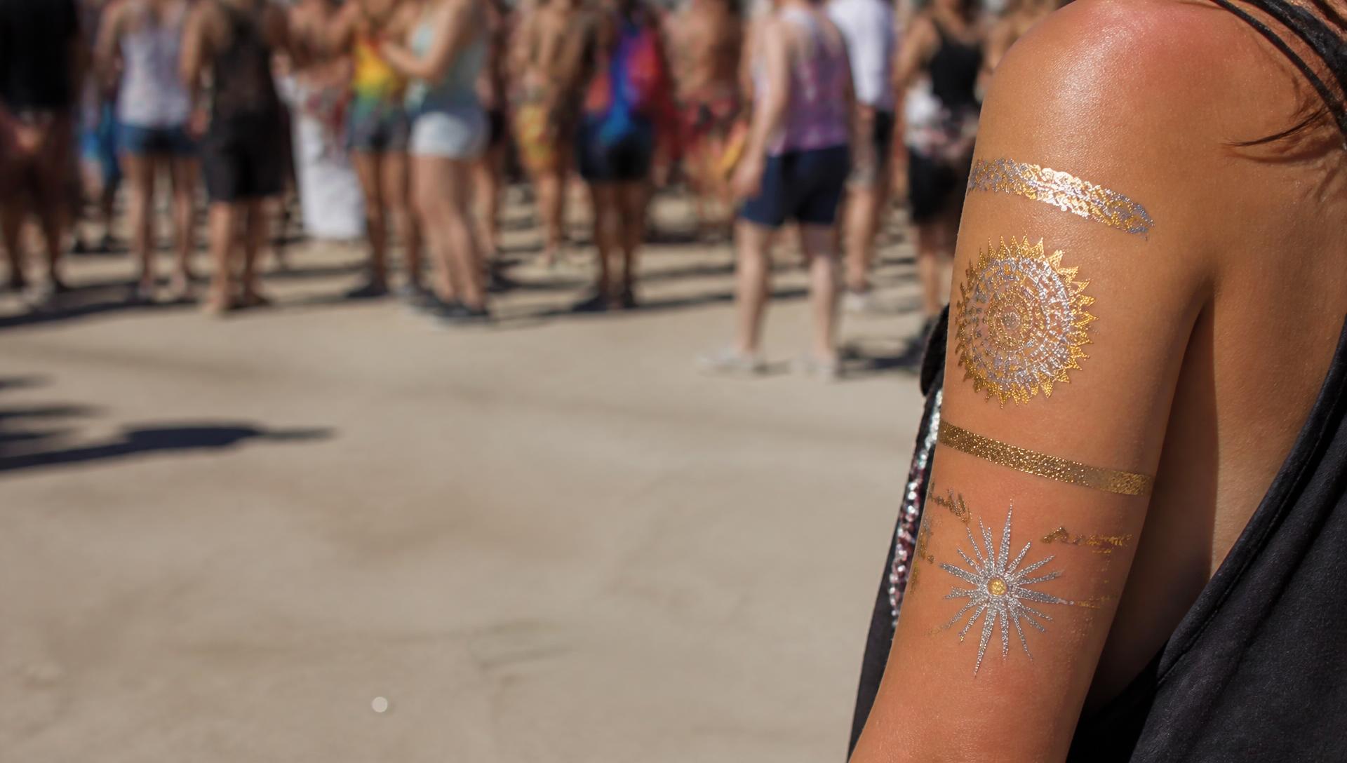 Glimmende gouden tijdelijke tattoo op een schouder in de zon