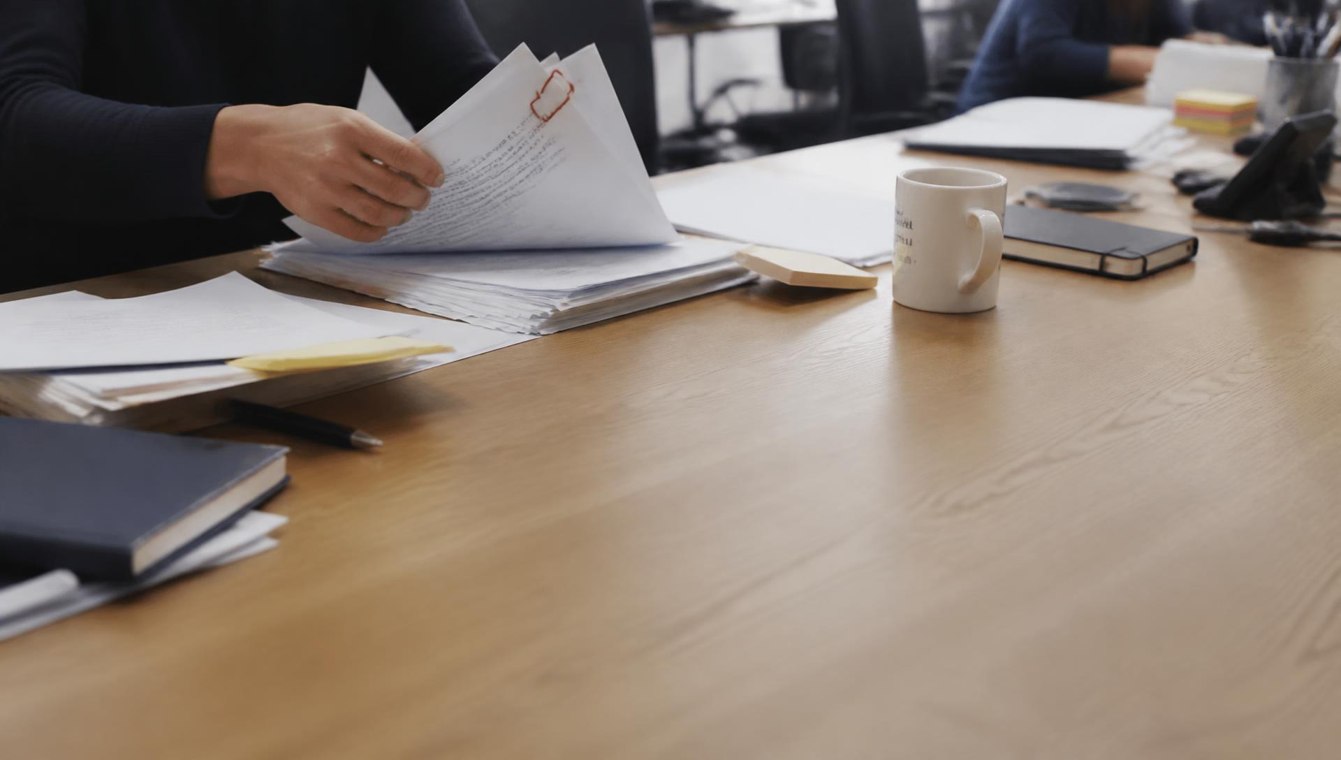 Iemand ordent documenten op een bureau met een gevormde paperclip