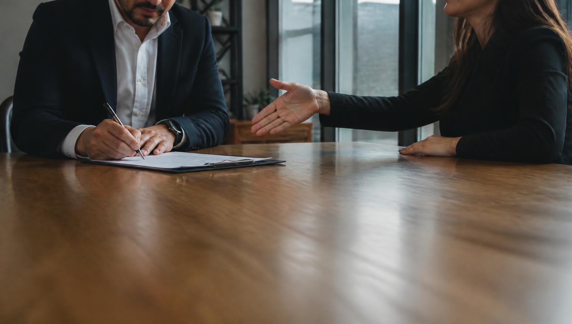 Twee mensen aan tafel zetten een handtekening bij het sluiten van een deal